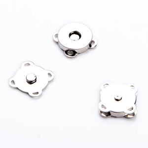 May include: Three silver magnetic clasps for sewing projects. Two clasps are square shaped with four loops, and one clasp is round with three loops.