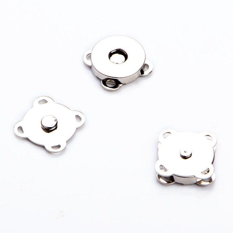 May include: Three silver magnetic clasps for sewing projects. Two clasps are square shaped with four loops, and one clasp is round with three loops.