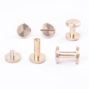 May include: A set of six brass screw-on post studs. The studs are in various stages of assembly, with some having the screw portion attached and others having the base plate attached.