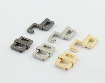 May include: Five metal clasps in different finishes: black, silver, and gold. Each clasp is made of two interlocking pieces.