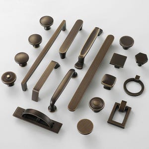 May include: A selection of bronze-coloured cabinet hardware, including knobs, pulls, and handles. The collection features various shapes and sizes, from round knobs to rectangular pulls and bar handles, all with a vintage aesthetic.