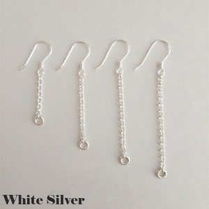 May include: Four silver chain earrings with a hook design. The earrings are of varying lengths, with a small ring at the bottom of each chain. The text "White Silver" is at the bottom of the image.