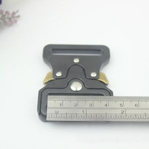 May include: A black metal buckle with a silver button and gold accents. The buckle is 1 1/2 inches wide.