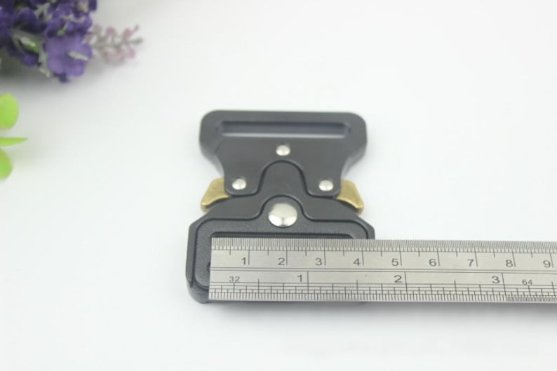 May include: A black metal buckle with a silver button and gold accents. The buckle is 1 1/2 inches wide.