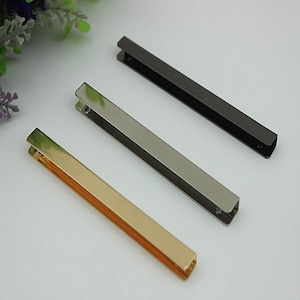 May include: Three metal rectangular bag handles in gold, silver, and black.
