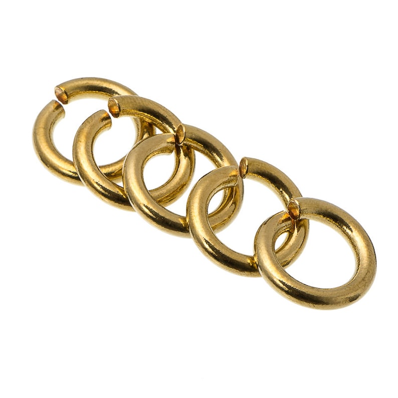 May include: Five gold jump rings, linked together, are shown against a white background. The rings are smooth and shiny.