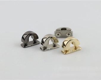 May include: Four metal hardware pieces, two are silver, one is gold, and one is black. Each piece has a curved top and a flat base. The pieces are used for attaching straps or other accessories to bags or other items.