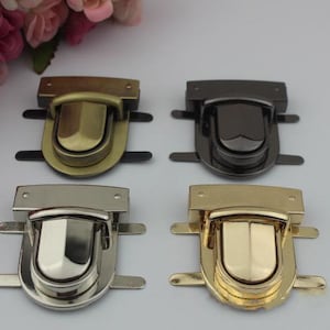 May include: Four different colored metal clasps for bags or purses. The clasps are in gold, silver, brass, and black.