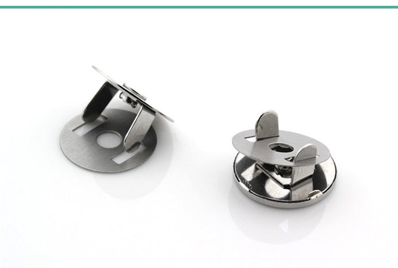 May include: Two silver metal snap fasteners, one with a raised lip and the other with a flat surface.