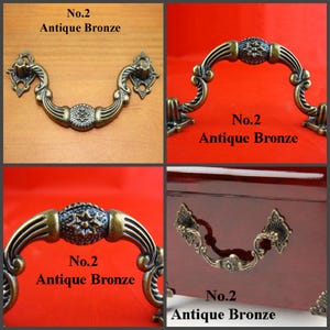 May include: An antique bronze drawer pull featuring a curved handle with ornate scrollwork and a central star-shaped medallion. The hardware includes two decorative mounting plates with intricate detailing. Text reads No.2 Antique Bronze.