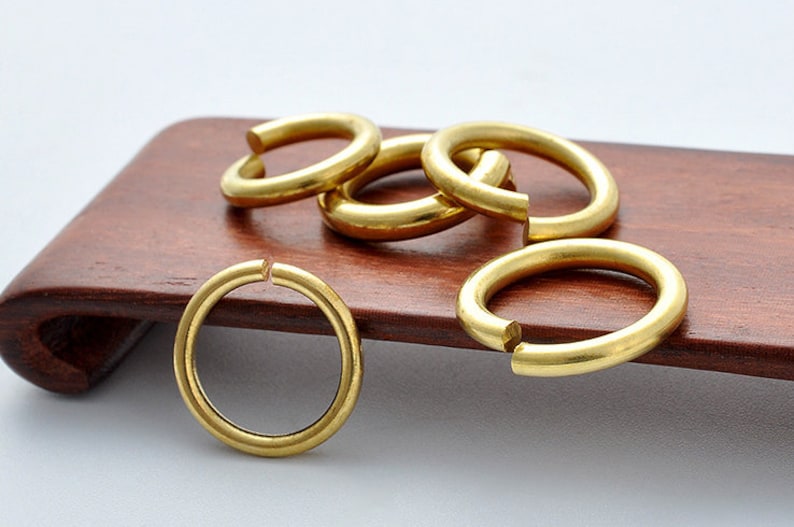 May include: Five gold-colored metal rings, some stacked on top of each other, on a wooden surface.