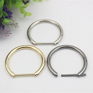 May include: Three metal rings in different finishes: gold, silver, and black. The rings are all the same size and have a flat bar across the opening.