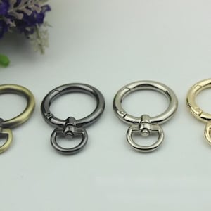 May include: Four metal key rings in different finishes: antique brass, black, silver, and gold. Each ring has a swivel clasp.