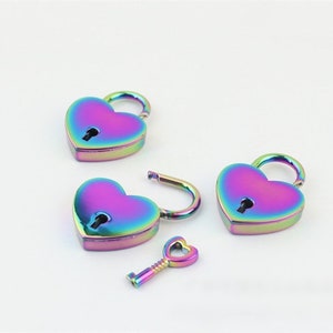 May include: Heart-shaped padlocks and a key with a rainbow iridescent finish. The locks are closed and open, showing the keyhole. The key is also heart-shaped. The items are on a white background.
