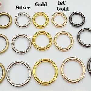 May include: Assortment of metal rings in various finishes, including antique bronze, silver, gold, KC gold, and gunmetal black. The rings are arranged in rows by color and are all the same size.