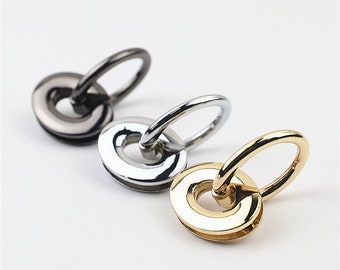 Puede incluir: Tres anillos metálicos con un diseño giratorio. Los anillos son de plata, oro y negro.