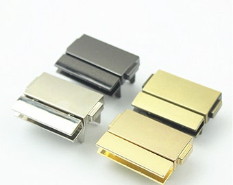 May include: Four metal clasps in different finishes: silver, gold, black, and gunmetal. Each clasp is rectangular and has a hinged design.