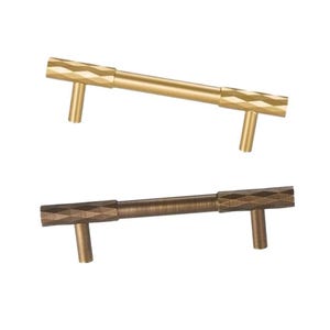 May include: Two cabinet pulls with a diamond-shaped pattern. The top pull is gold and the bottom pull is brown.