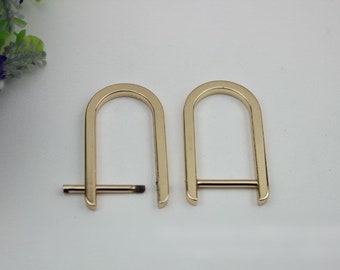 May include: Two gold-colored metal D-rings with a straight bar connecting the two ends of the ring. The rings are about 2 inches in diameter.