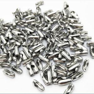 May include: A pile of silver metal connector links for chains or cords. The links are cylindrical and have a twisted design.