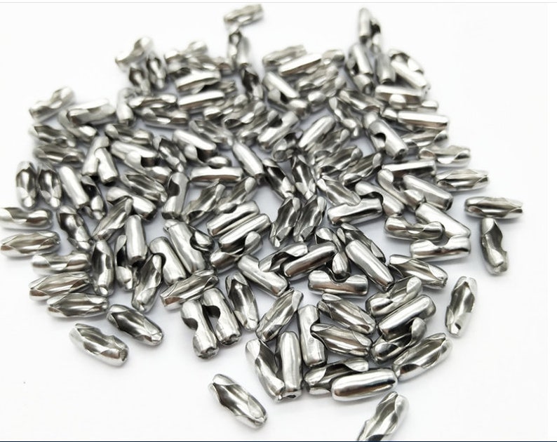 May include: A pile of silver metal connector links for chains or cords. The links are cylindrical and have a twisted design.