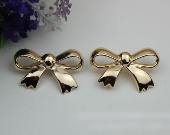 May include: A pair of gold-tone bow-shaped earrings.