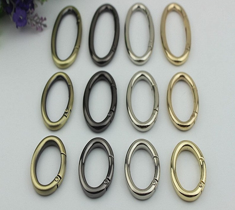 May include: Twelve oval-shaped metal key rings in four different finishes: antique brass, black, silver, and gold. The key rings have a spring-loaded clasp.