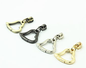 May include: Four heart-shaped zipper pulls in gold, silver, and black metal.