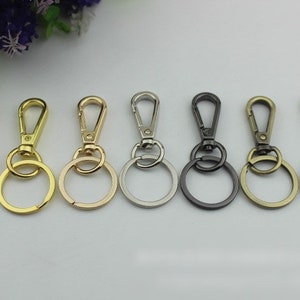 May include: Seven keychains with different metal finishes. The keychains have a round ring and a swivel clasp.