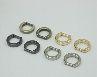 May include: Eight metal rings in different colors, including gold, silver, black, and bronze. The rings are all the same size and shape, and they have a small opening on one side.