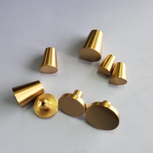 May include: A set of eight gold-toned cabinet knobs and pulls. The knobs are round and the pulls are cone-shaped.