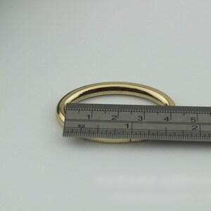 May include: A gold metal ring with a diameter of approximately 3 inches, measured with a ruler.