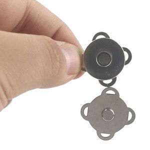 May include: A set of two silver magnetic snap closures. The closures are shaped like a four-pointed star. The closures are designed to be sewn onto fabric.