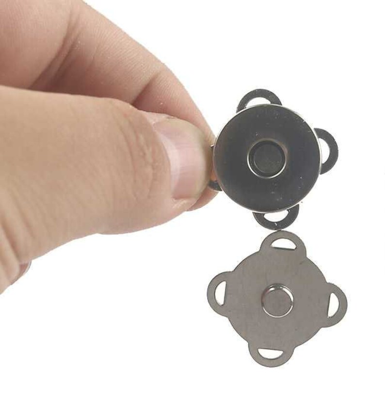 May include: A set of two silver magnetic snap closures. The closures are shaped like a four-pointed star. The closures are designed to be sewn onto fabric.