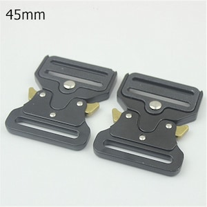 May include: Two black metal belt buckles with gold accents. The buckles are 45mm in size.
