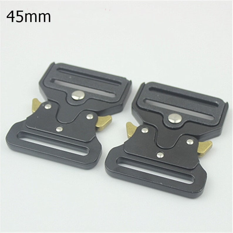 May include: Two black metal belt buckles with gold accents. The buckles are 45mm in size.