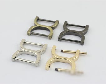 May include: Four metal D-ring buckles in different finishes: gold, silver, antique brass, and black. The buckles are all the same size and shape, with a double D-ring design.