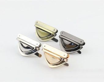 May include: Four metal clasps in different finishes: silver, gold, antique brass, and black. Each clasp has a rectangular plate and a triangular shape.