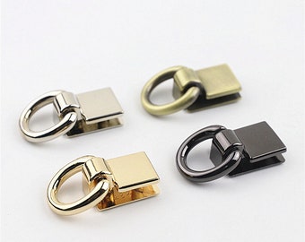 May include: Four metal D-ring connectors in silver, antique brass, gold, and black. Each connector has a rectangular base and a circular ring. The connectors are arranged on a white surface.
