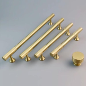 May include: Five gold-toned cabinet pulls with a ribbed design and a single round knob with a ribbed design.