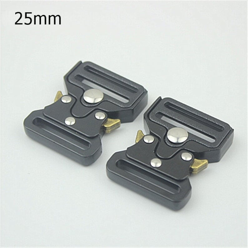 May include: Two black metal belt buckles with silver and gold accents. The buckles are 25mm wide.