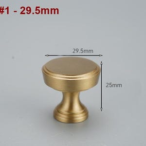Op de afbeelding: Een gouden kastknop met een ronde bovenkant en een cilindrische basis. De knop is 29,5 mm in diameter en 25 mm hoog. #1 - 29,5 mm