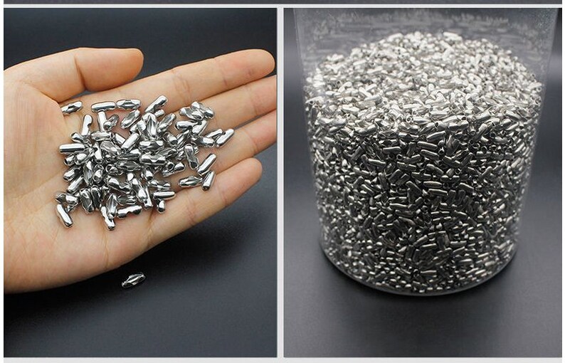 May include: A large quantity of small, silver-colored metal beads in the shape of a capsule. The beads are shown in a hand and in a clear container.