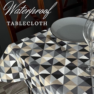 May include: A waterproof tablecloth with a geometric pattern in shades of grey, black, and beige. The text "Waterproof TABLECLOTH" is displayed in white script. A grey plate, fork, and wine glass are on the table.