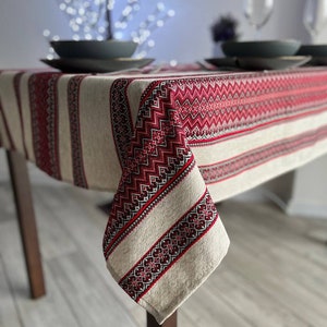 May include: Red and white linen tablecloth with embroidered geometric patterns. The tablecloth is draped over a wooden table with a corner hanging down. The text "Red No. 1" is visible in the bottom right corner of the image.