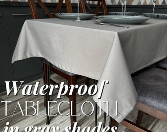 May include: A gray tablecloth with a waterproof finish, set on a table with two chairs. The tablecloth is draped over the chairs and has black hairpin legs. The text "Waterproof Tablecloth in gray shades" is visible in the image.