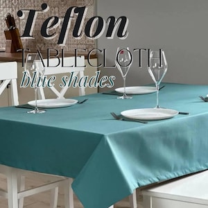 Könnte beinhalten: Eine tealfarbene Tischdecke mit Teflon-Beschichtung, gedeckt für ein Abendessen mit weißen Tellern und Weingläsern. Die Tischdecke liegt auf einem weißen Tisch mit weißen Stühlen.