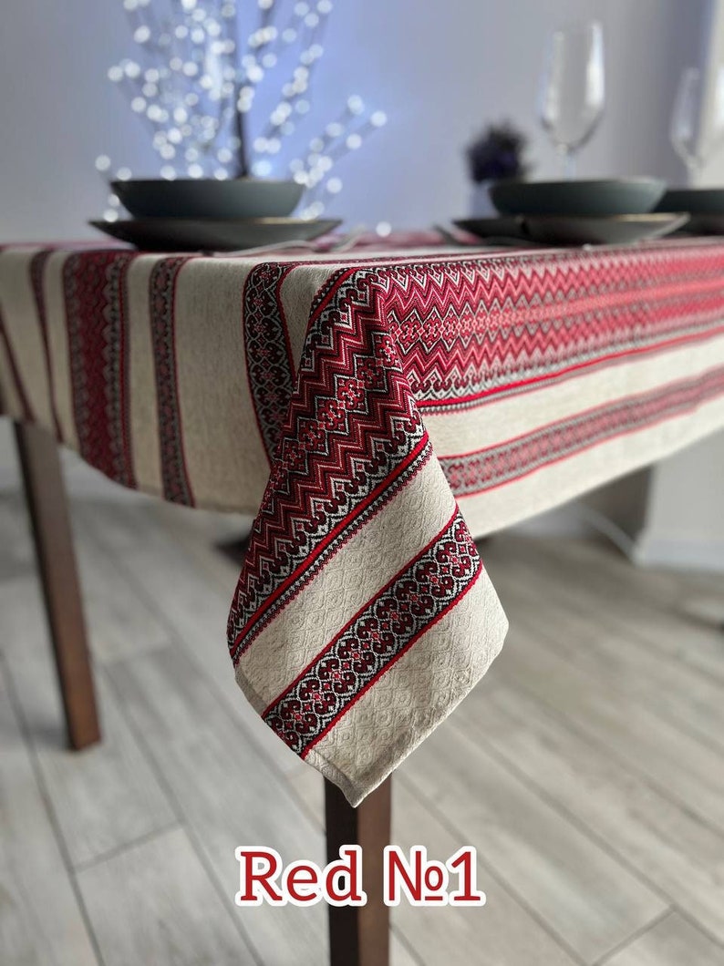 May include: Red and white linen tablecloth with embroidered geometric patterns. The tablecloth is draped over a wooden table with a corner hanging down. The text "Red No. 1" is visible in the bottom right corner of the image.