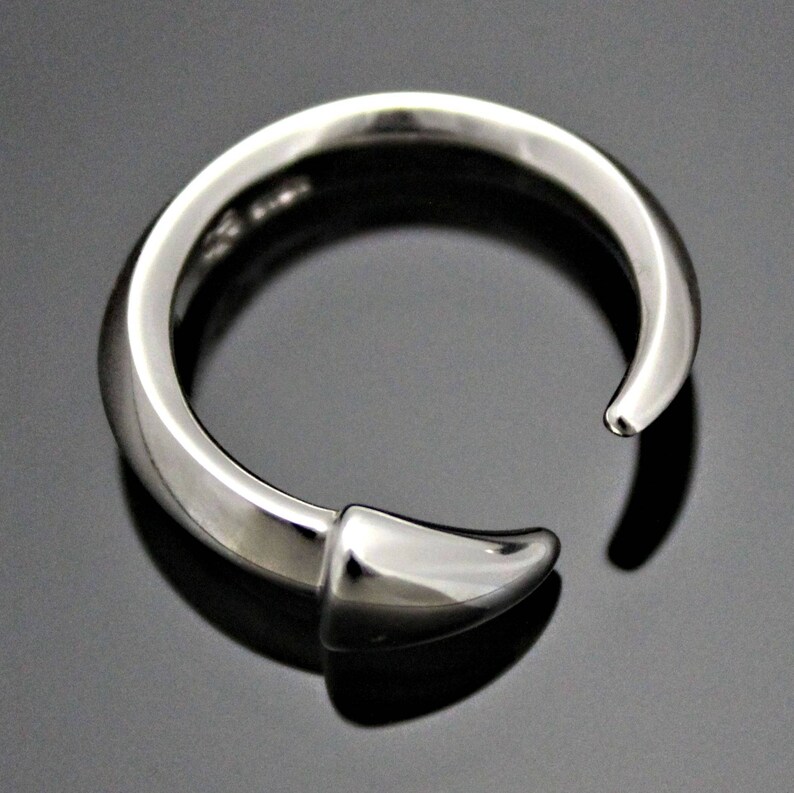 Puede incluir: Un anillo de plata con un dise&ntilde;o puntiagudo y curvo. El anillo est&aacute; abierto por un lado y tiene un acabado liso y pulido.