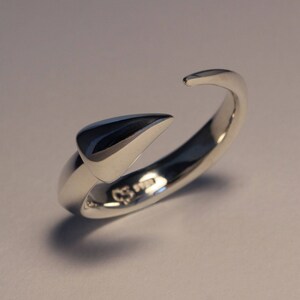 Puede incluir: Un anillo de plata con un dise&ntilde;o puntiagudo y triangular. El anillo est&aacute; abierto y tiene un acabado liso y pulido.